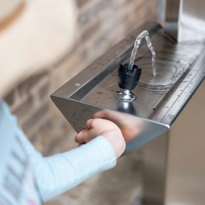 child using water cooler to get a drink of water in a park